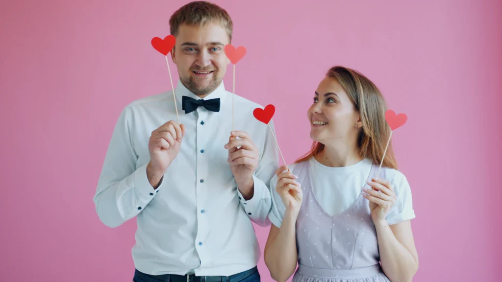 Couple posing with heart props at a classic photo booth