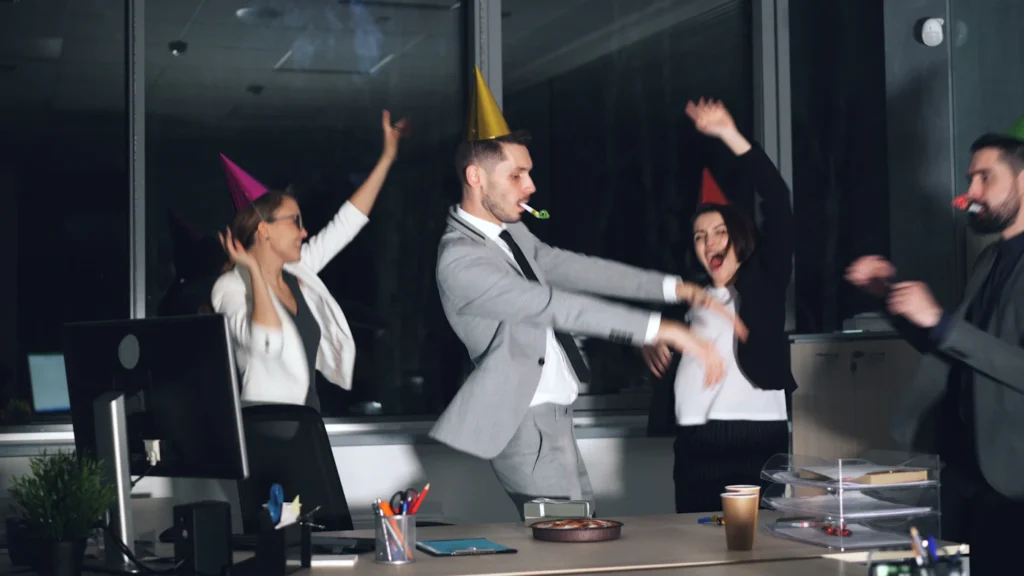 Team celebrating at a corporate office party with party hats