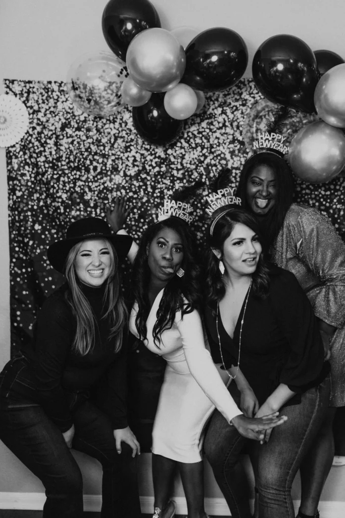 Guests posing in front of a sequin and balloon backdrop